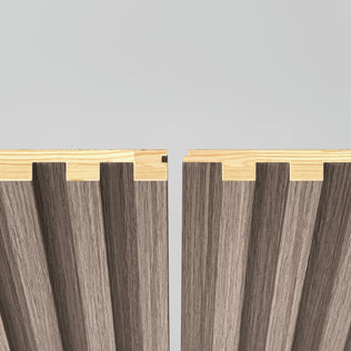 Two Panolok 30.67 ft wall panel kits by Artika, each with light oak edges and textured brown surfaces, stand vertically with a small gap, showcasing interlocking zigzag edges—reflecting minimalist Scandinavian style.