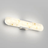 A modern wall-mounted light fixture with a rounded, elongated design and a marbled white glass cover, emitting a soft, warm glow against a light gray wall.