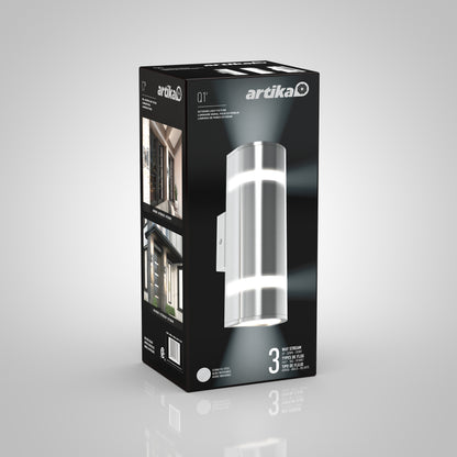 A black box packaging for the Artika Q1 indoor-outdoor wall light, displaying the silver cylindrical fixture and images of the light installed on house exteriors.