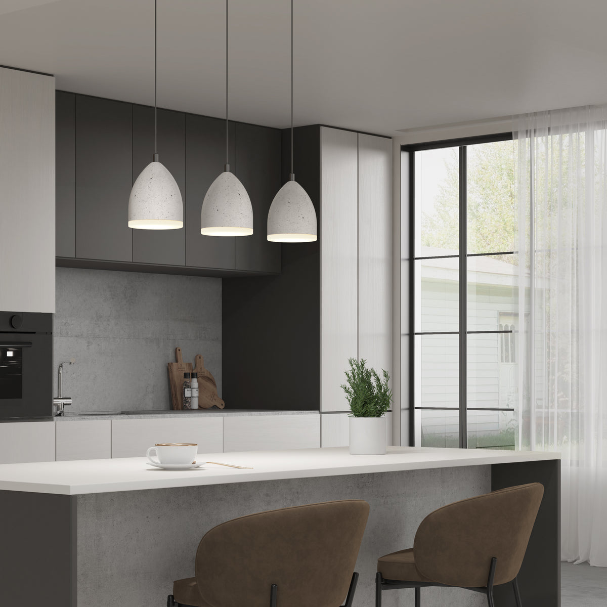 A modern kitchen with pendant lights over a white island, two brown chairs, a cup and saucer, a plant pot, and large windows with sheer curtains letting in natural light.