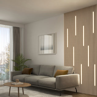 A modern living room with a gray sofa, brown cushions, Artika Lumilok LED Wall Panel Light for Sonolok, round table, plant, and curtains.