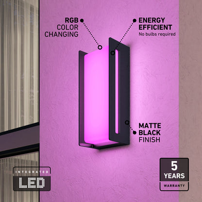 The Artika Ryker smart RGB indoor-outdoor wall light glows pink on a textured wall, featuring energy-efficient RGB color changing, a matte black finish, and 5-year warranty. A window is partially visible on the left.