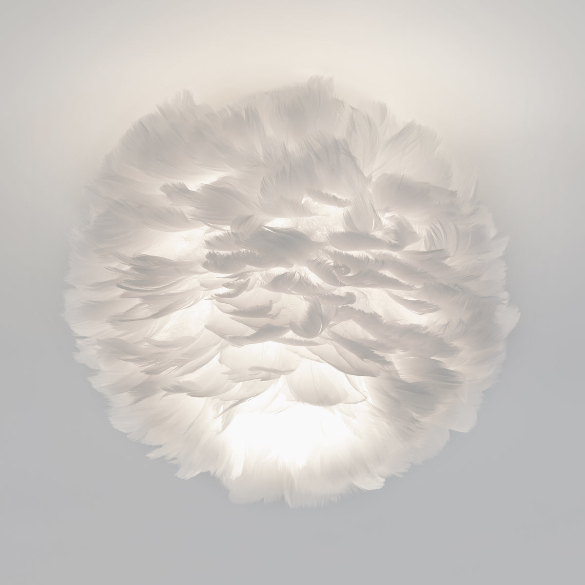 A round, white ceiling light fixture made of layered, soft feathers, creating a fluffy, cloud-like appearance with gentle, diffused illumination.