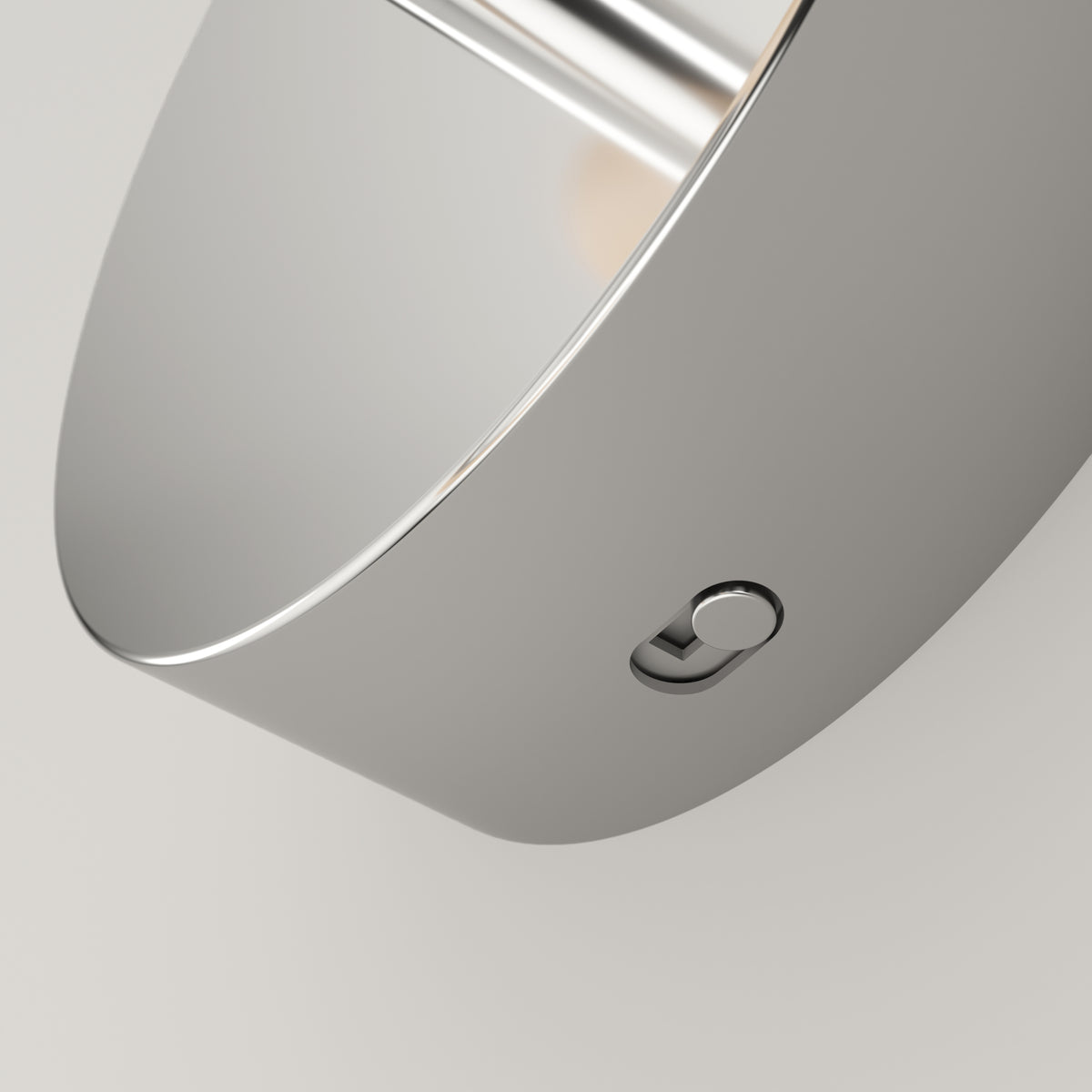 Close-up of a sleek, modern metallic object with a smooth, curved surface and a small round button on its side, set against a plain light background.