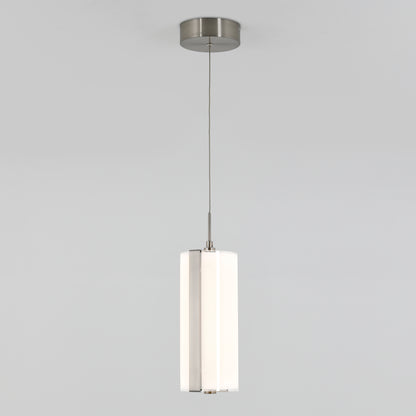 The Artika Subway Round Mini LED pendant light features a cylindrical white shade and metallic accents, suspended from a slim cord attached to a round ceiling mount against a plain gray background.
