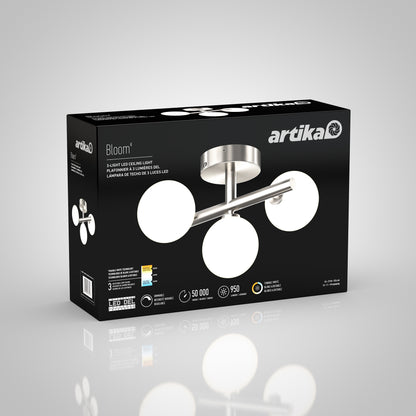 The black Artika box displays the Bloom LED flush mount, featuring three round white lights and a brushed steel base. Packaging includes product details and features in both English and French.