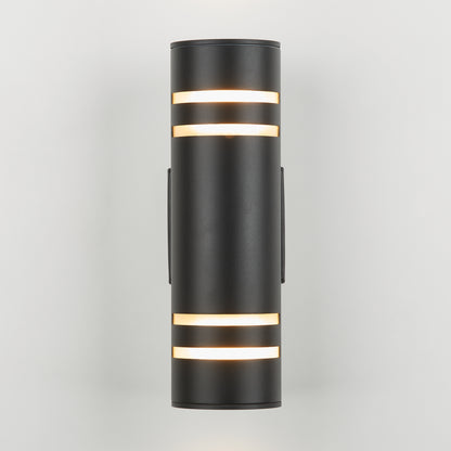 The Artika V3 indoor-outdoor wall light is a modern black cylindrical sconce with horizontal slits near the top and bottom, casting warm light against a plain white background.