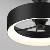 A close-up of a modern ceiling fan with a circular black frame and integrated white LED light, showing the fan blades inside the illuminated ring against a neutral gray background.