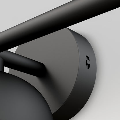 Close-up of the Artika Boden LED mid-century bathroom vanity light 5 CCT, a modern matte black wall-mounted fixture with cylindrical base and rod, set against a plain light gray background.