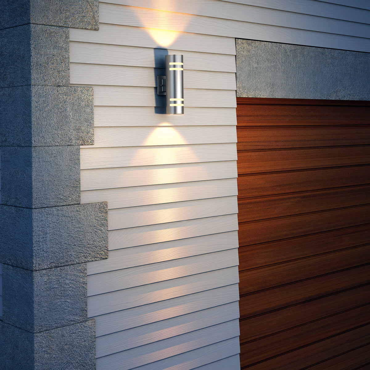 Artika’s Voltz indoor-outdoor wall light, with a modern cylindrical design, casts up and down beams on white siding beside a closed wooden garage door and gray stone corner.
