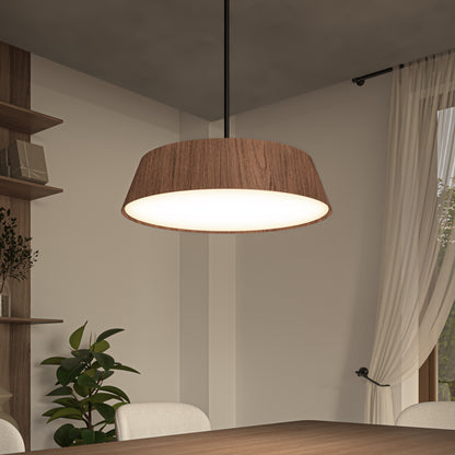 A modern dining room features the Artika Dunham LED Pendant 5 CCT above a wooden table, paired with beige chairs, a potted plant in the corner, wall shelves, and sheer white curtains.