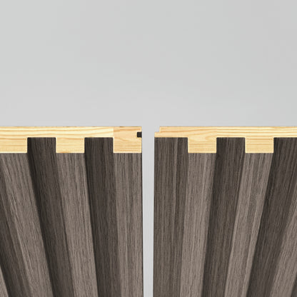 Two interlocking wooden panels with a grooved pattern are shown, featuring a light wood top edge and gray vertical ridges, positioned with a small gap between them against a plain background.