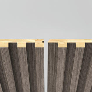 Two Artika Panolok 30.67 ft wall panel kit panels, featuring a light wood top edge and dark vertically grooved surfaces, are positioned close together on a plain light background. Pack of 8 included.