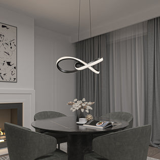 A modern dining area with a round black table, four dark green chairs, and the Morgan LED contemporary pendant light by Artika. The space features gray curtains, abstract wall art, a fireplace, and a table styled with magazines and decor.