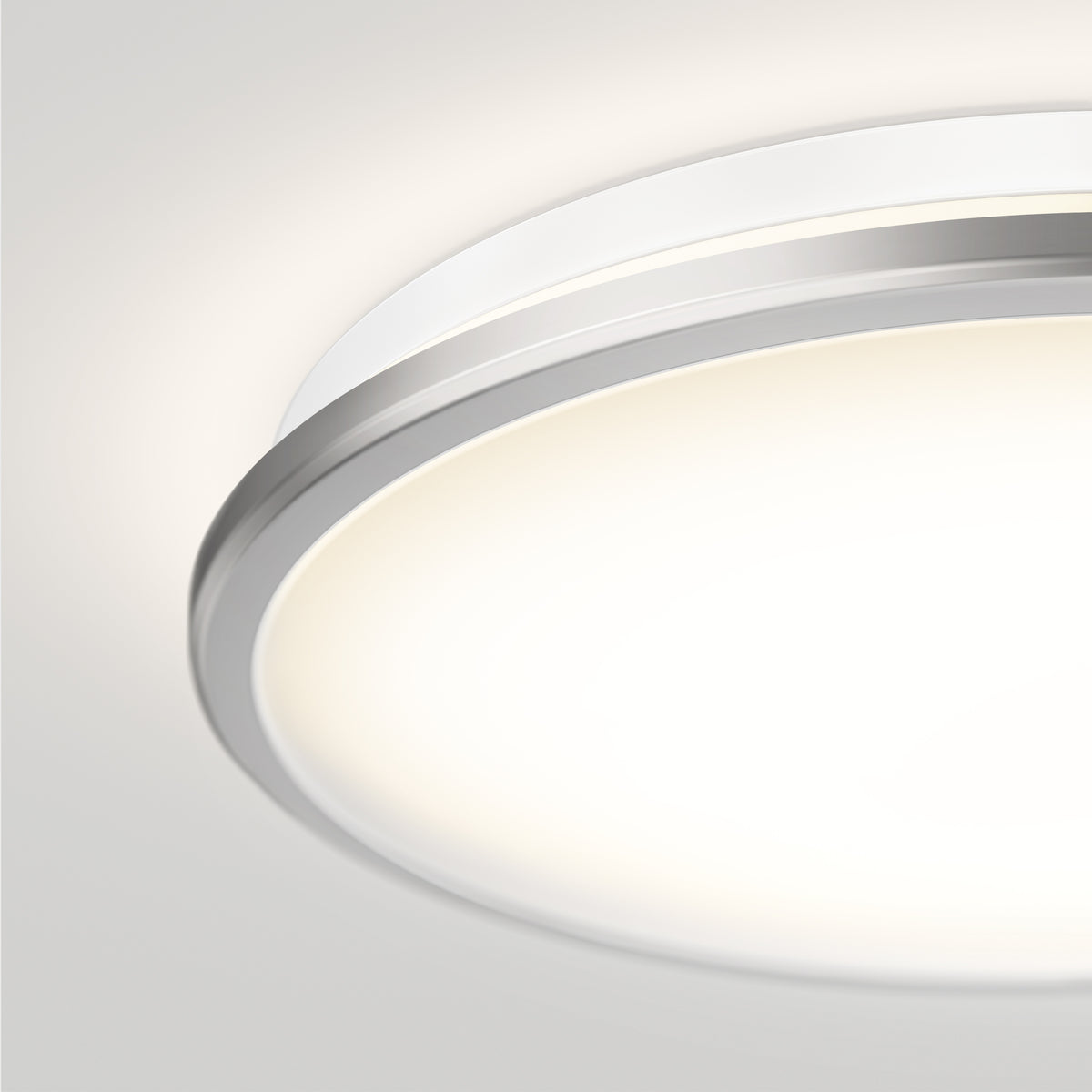 A close-up of a modern, circular ceiling light fixture glowing with soft white light against a smooth, light-colored ceiling.