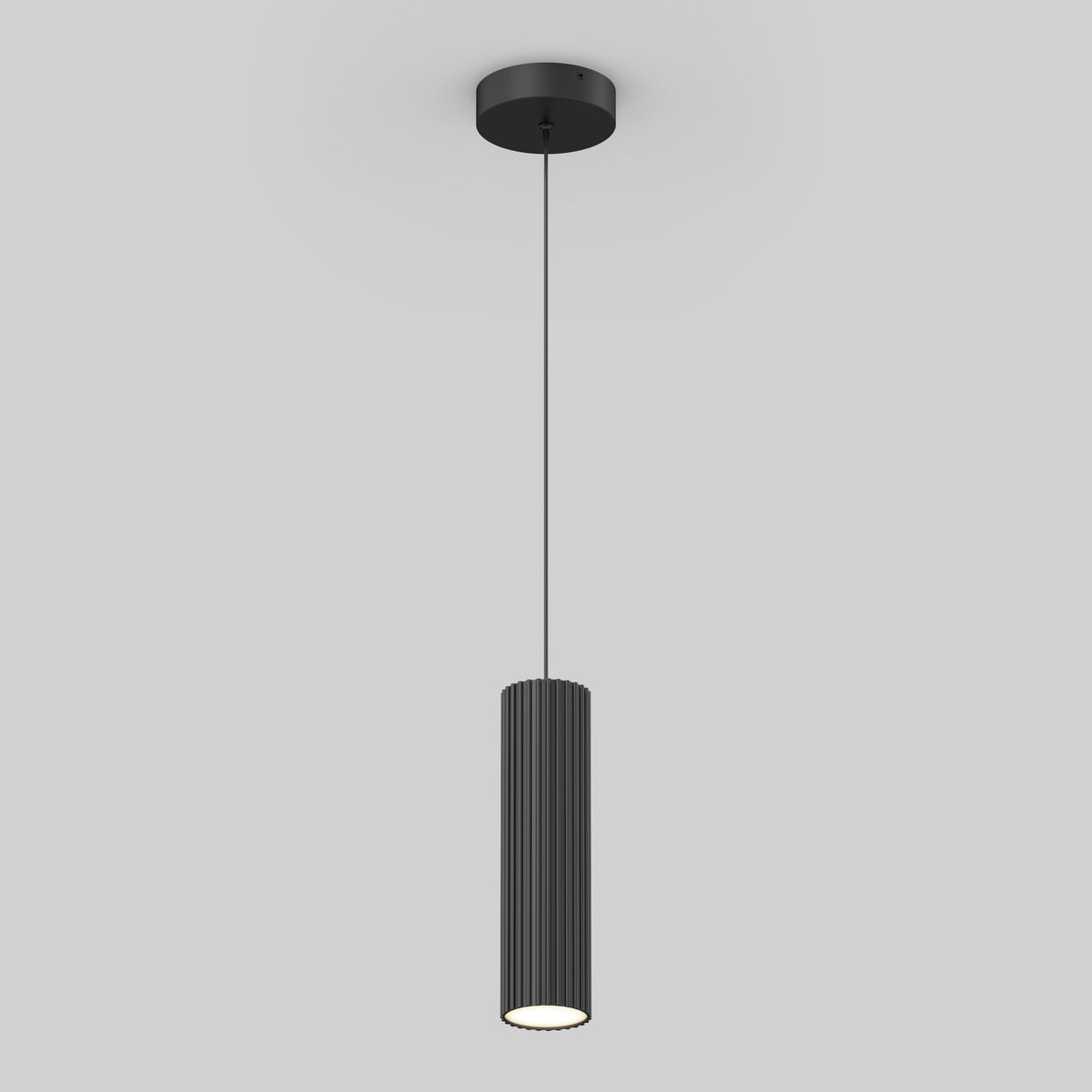 A modern black pendant light with a cylindrical, ribbed shade hangs from the ceiling by a thin cord against a plain light gray background.