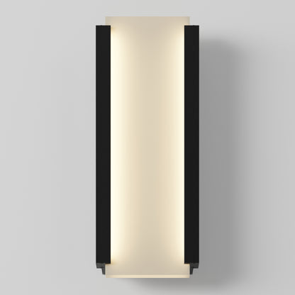 The Artika Blade indoor-outdoor LED wall light features a modern rectangular design with a black frame and frosted white panel, mounted vertically on a light gray wall to emit a soft, diffused glow.