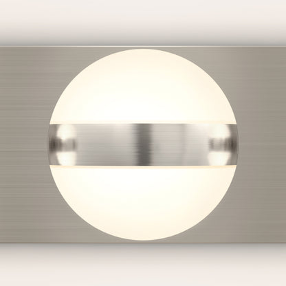 The Artika Baldric LED modern bathroom vanity light features a glowing round white light, partially covered by a horizontal brushed metal band on a matching rectangular backplate.