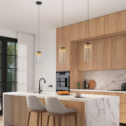 Modern kitchen with light wood cabinets, marble island and backsplash, two upholstered bar stools, a built-in oven, large windows overlooking greenery, and three Artika Hanson 1-light LED pendant 5 CCT lights above the island.