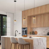 Modern kitchen with light wood cabinets, marble countertops, and island with two beige upholstered stools. Three pendant lights hang above the island. Built-in oven, sink, and fruit bowl are visible. Large window lets in natural light.