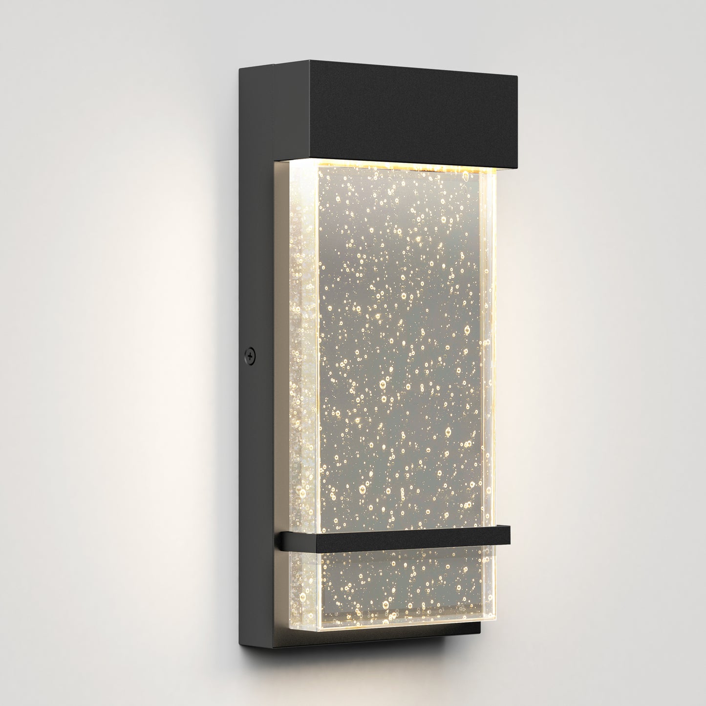 The Artika Skyler indoor-outdoor LED wall light features a modern rectangular black frame and a frosted bubble glass panel, emitting softly diffused warm white light.