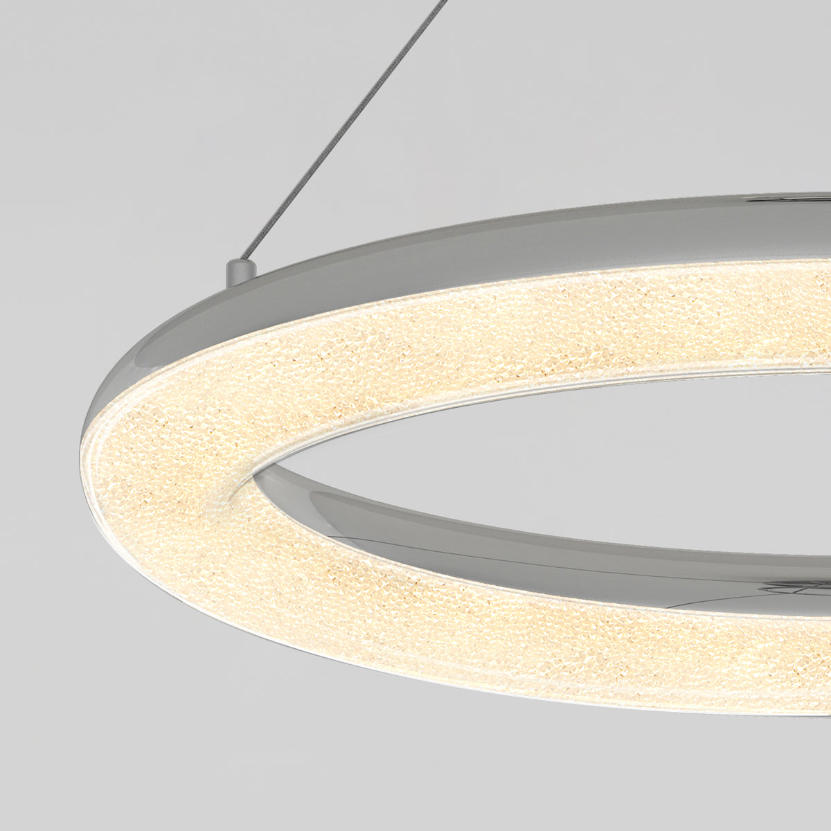 A close-up view of a modern, circular LED pendant light with a textured, illuminated surface, suspended by a thin cable against a plain light gray background.