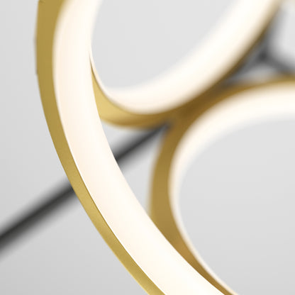 Close-up of two intersecting circular golden rings with a smooth, matte finish—a modern, abstract look for the Artika Mini Luxury LED pendant light against a blurred light gray background.