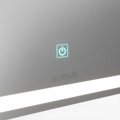 A close-up of the Artika Emeraude dimmable LED mirror 3 CCT, featuring a glowing blue power button above the brand name and a horizontal LED light strip at the bottom.