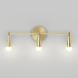A modern wall sconce with a brushed gold finish, featuring three evenly spaced cone-shaped light fixtures, each with a round bulb, mounted on a circular backplate against a light gray wall.