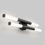 A modern wall sconce with two parallel black cylindrical bars, each with white illuminated ends, mounted on a round black base against a plain light gray background.