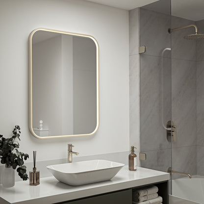 Modern bathroom features the Artika Royce Dimmable LED Mirror (3 CCT, horizontal/vertical mount) with defogger above a white countertop, vessel sink, faucet, towel shelf, and glass shower enclosure. Plants and toiletries complete the look.