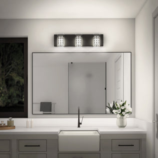 Modern bathroom with a large mirror, rectangular sink, black faucet, white countertop, and the Artika Crystal Cube LED bathroom vanity light 5 CCT above the mirror. A vase with white flowers sits on the counter next to the sink.
