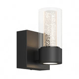 Modern wall sconce with a black square base and a cylindrical glass shade filled with small bubbles, housing a vertical LED light inside.