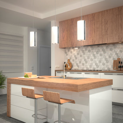 Modern kitchen with white cabinets, wood accents, a hex tile backsplash, and an island with a sink. Two wooden barstools face the island, illuminated by three Artika Subway Round Mini LED pendant lights above. A plant sits in the corner.