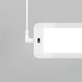 A close-up of a modern rectangular ceiling light with a bright white panel, a visible power cable attached at the top left corner, and a gray background.