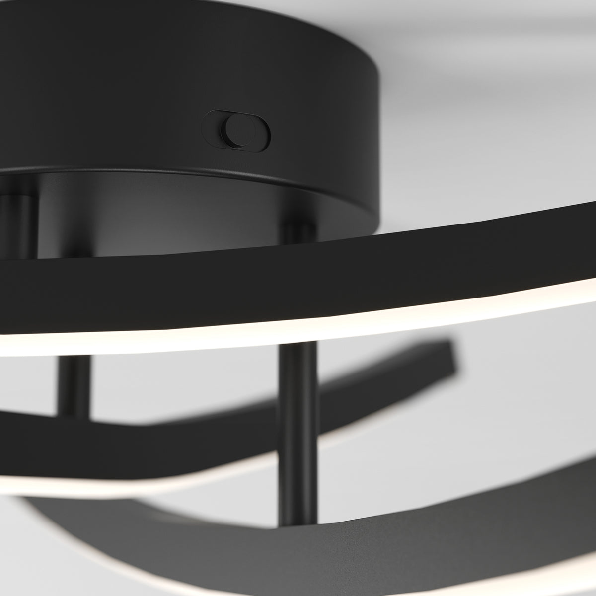 Close-up of a modern black ceiling light fixture with curved LED light strips and a round base against a white ceiling.