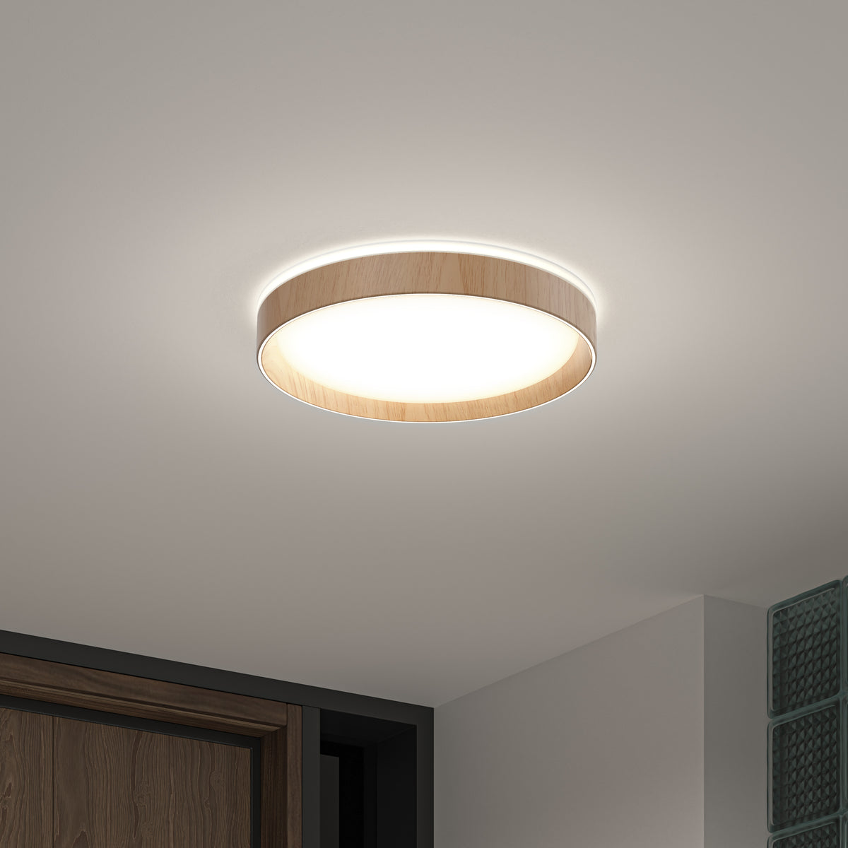 A modern round ceiling light with a wooden trim, emitting a soft, bright glow, is mounted on a white ceiling near a doorway and glass blocks.