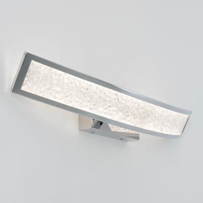 The Artika Glitter LED bathroom vanity light features a modern wall-mounted design with a curved chrome frame, textured frosted glass panel, and minimalist square base for a stylish accent on your white wall.