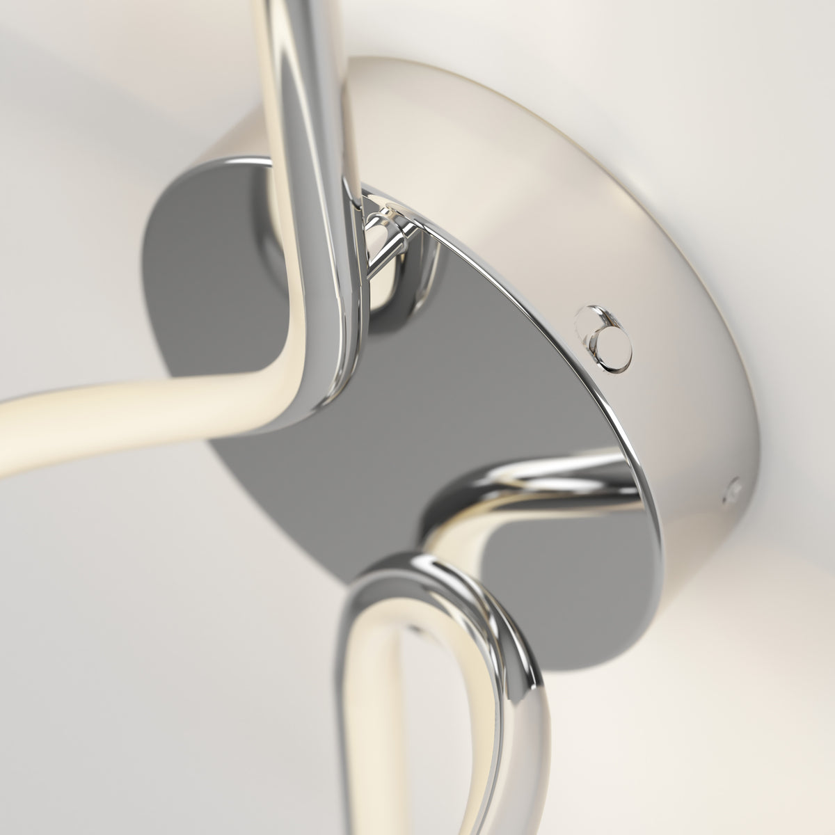 Close-up of a modern, chrome-finished ceiling light fixture with curved LED arms attached to a round metallic base, mounted on a white ceiling.