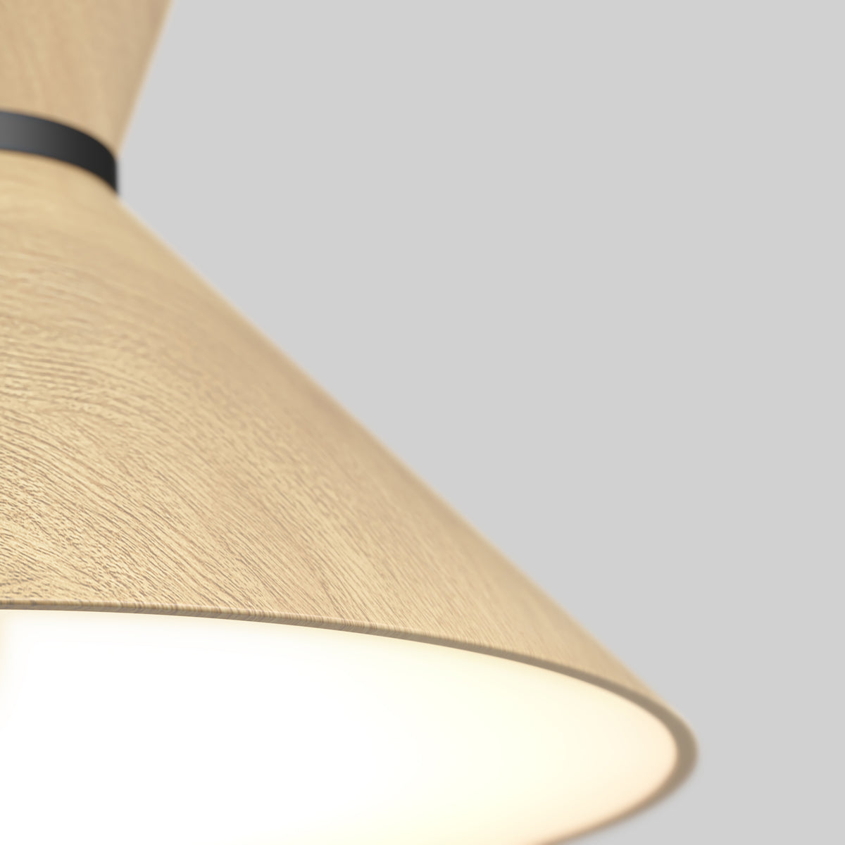 Close-up of a modern light fixture with a conical, light wood-textured shade and black band, emitting a soft white glow against a plain light gray background.