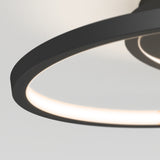 Close-up of a modern circular ceiling light fixture with a black frame and integrated LED, emitting a soft, even glow against a white ceiling.