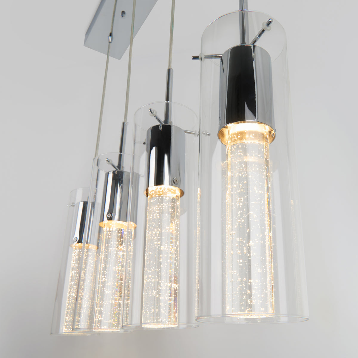The Artika Bubble Flow 4-light pendant features four modern cylindrical glass shades with chrome fixtures, each with illuminated LED bubbles inside, creating a sleek and contemporary look.