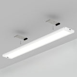 A white rectangular LED ceiling light fixture is shown mounted to a grey ceiling with two metal brackets and visible screws for installation. The light is turned on, emitting a bright glow.