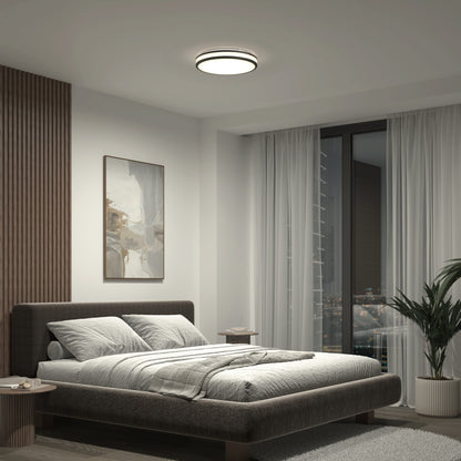 Modern bedroom featuring a large bed, abstract wall art, sheer floor-to-ceiling curtains, potted plant, and minimal furniture, lit by the Artika Hemisphere 15 in. LED flush mount light 5 CCT with adjustable brightness.