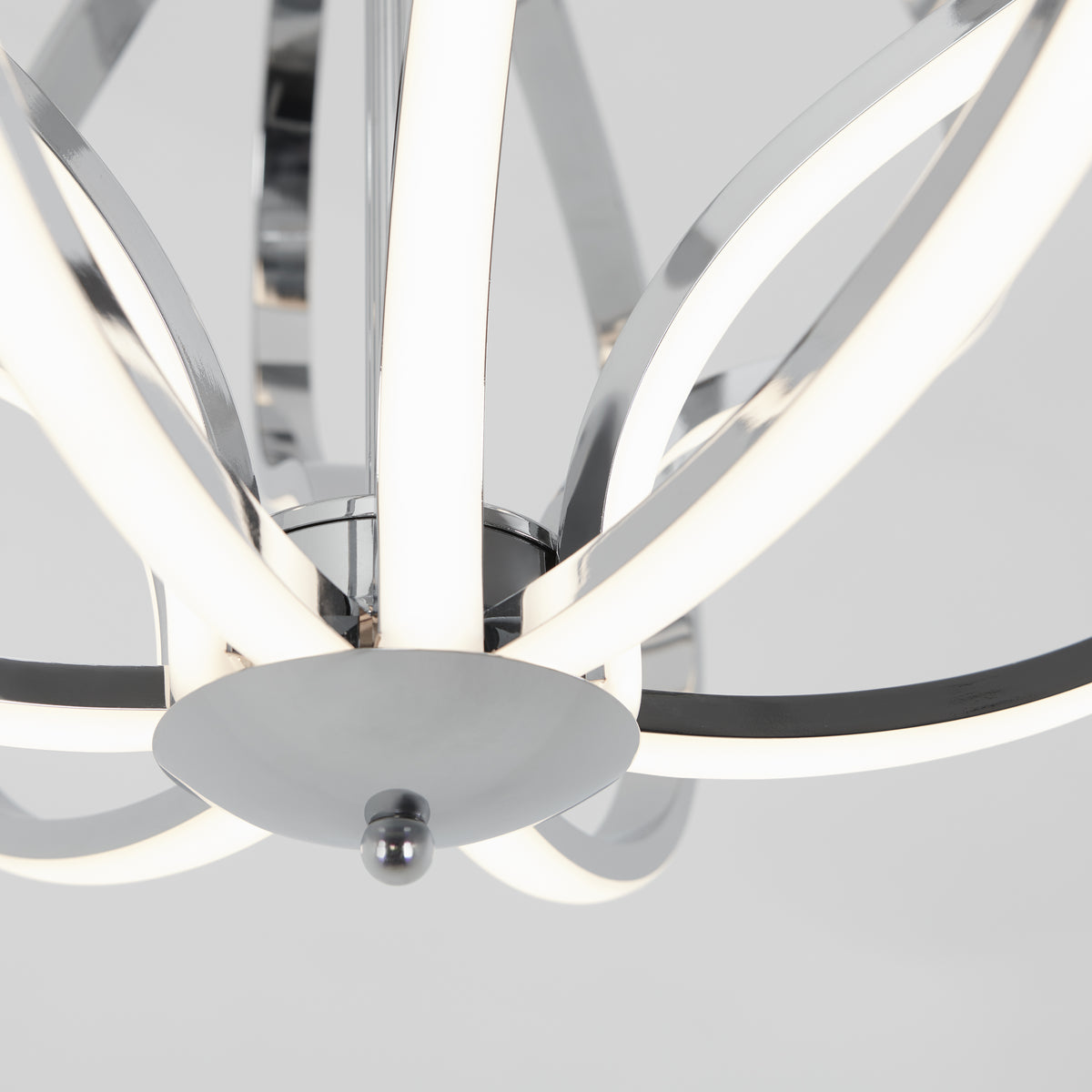 Close-up of a modern chandelier with curved, polished chrome arms and integrated LED light strips, set against a light grey background.