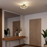 A modern entryway with a wooden console table, decorative vases, a large wall mirror, two wooden doors, green plants, and a sculptural ceiling light fixture.