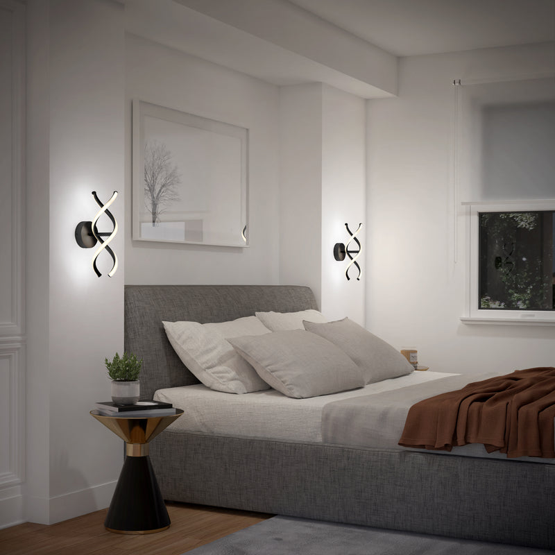 A bed with pillows and a table with plants, softly illuminated by the Artika DNA modern LED wall sconce 3 CCT for a cozy ambiance.