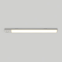 The Artika Outline under cabinet LED light 3CCT, a slim rectangular fixture, is mounted on a plain light gray ceiling. It emits a soft, even glow when turned on and features a small control button at one end.