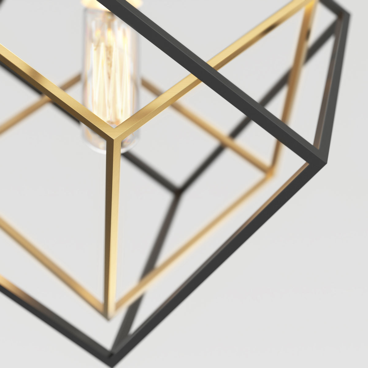 Close-up of a modern geometric pendant light featuring intersecting black and gold metal frames with an exposed vintage-style bulb inside against a plain light background.