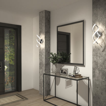 Modern entryway with a black console table holding decor items, a large rectangular mirror, and two sculptural wall lights mounted on concrete pillars beside the table. A glass door lets in natural light.